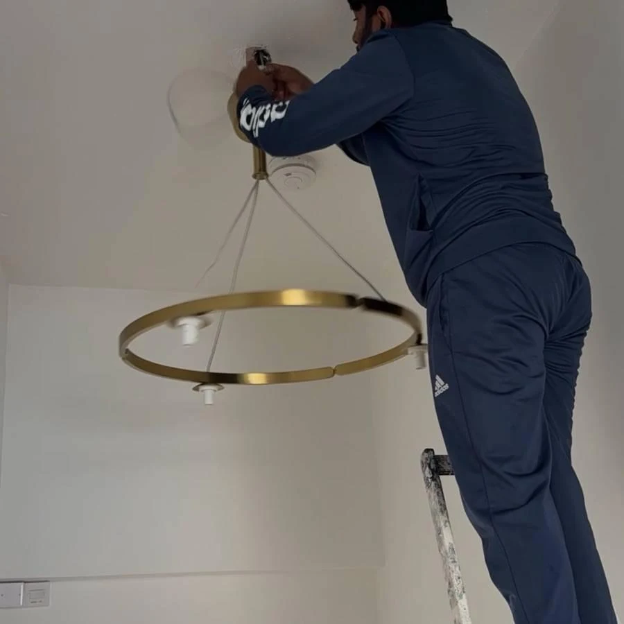 Handyman installing a gold ring pendant light on a ceiling