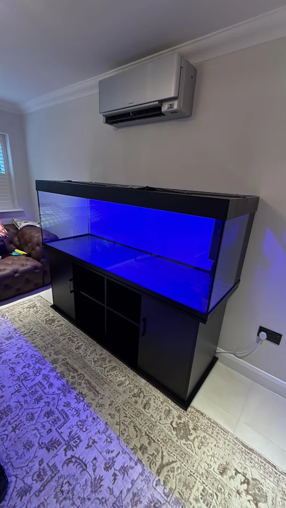 Large aquarium unit assembled beneath a wall mounted air conditioning unit