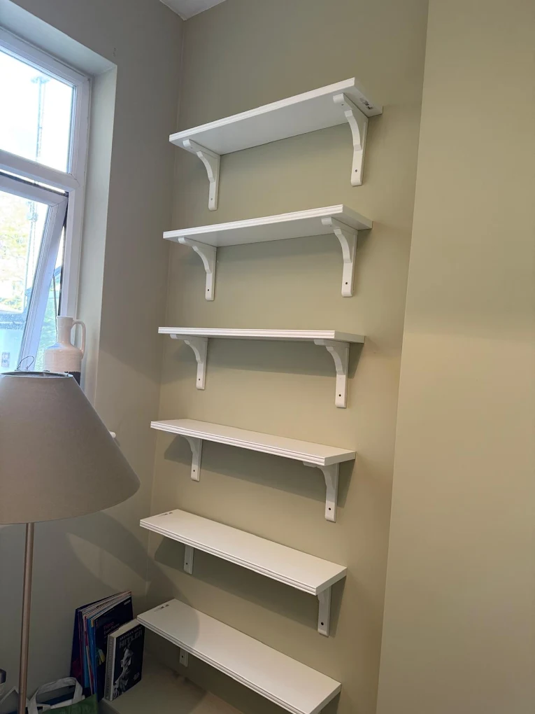 Six white wall shelves mounted level in an alcove